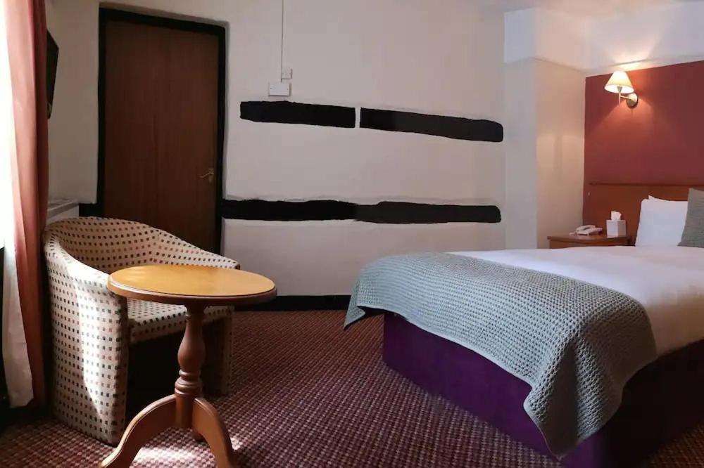 a hotel room with a bed and a small table at The Tudor Hotel in Harrow