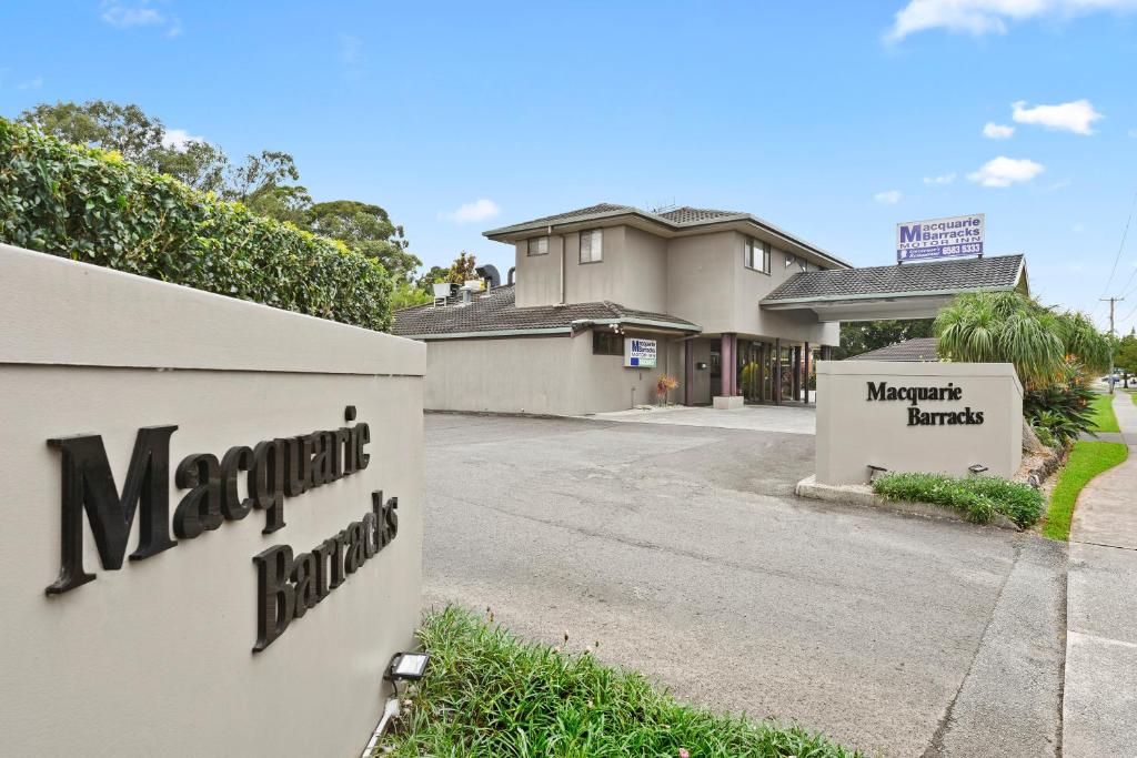 uma casa com uma placa ao lado de uma rua em Macquarie Barracks Motor Inn em Port Macquarie