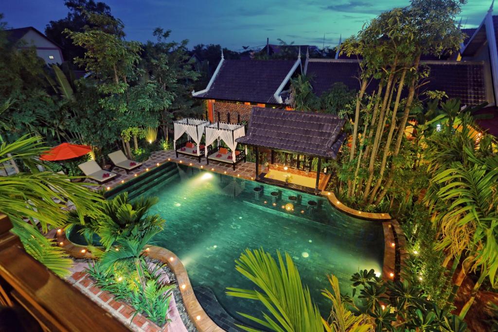 
a garden scene with a pool of water and trees at Villa Indochine D'angkor in Siem Reap
