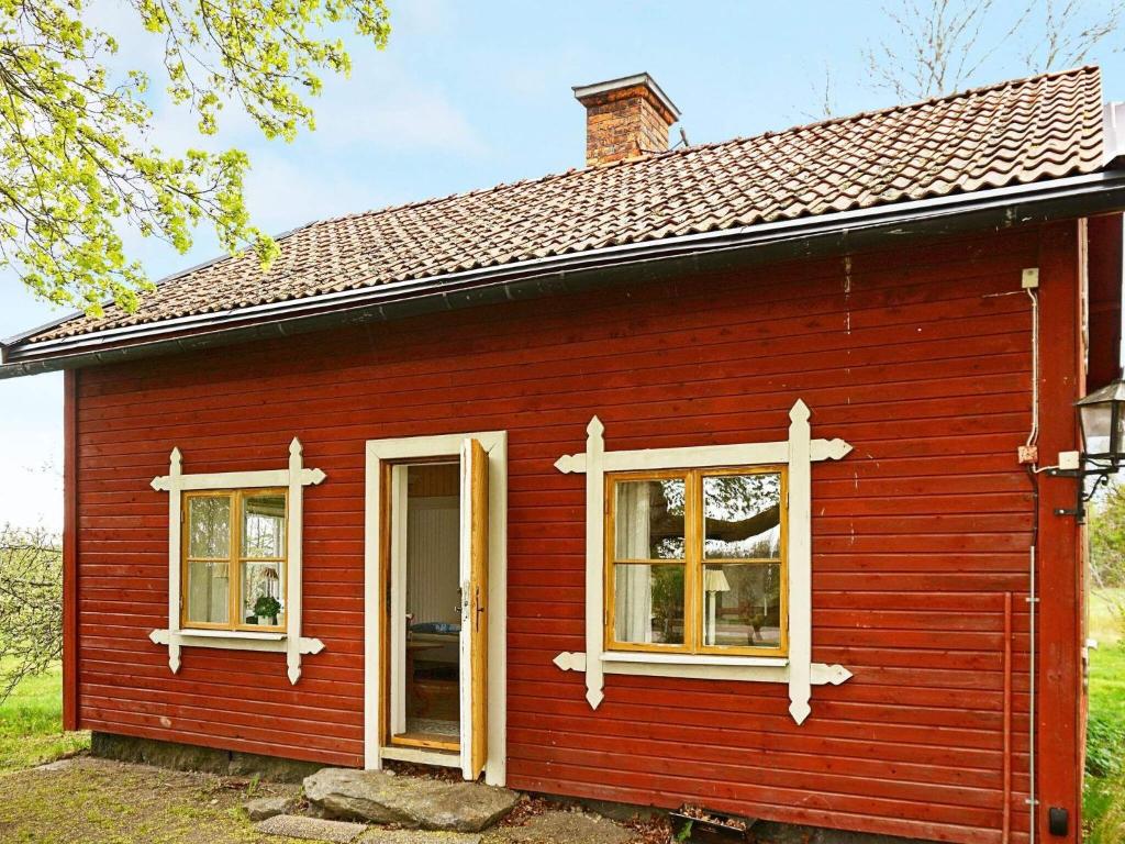 una casa roja con dos ventanas en un patio en Holiday home FLEN IV en Flen