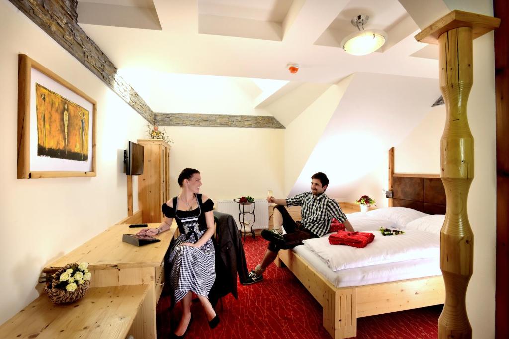 un hombre y una mujer sentados en un dormitorio en Lorenzer Schlafstubn en Sankt Lorenzen im Mürztal