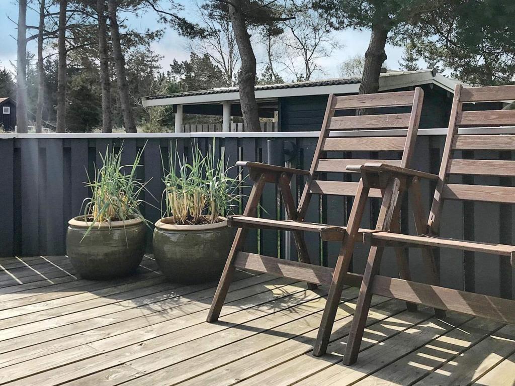 une chaise en bois et des plantes en pot sur une terrasse dans l'établissement Three-Bedroom Holiday home in Blåvand 21, à Blåvand