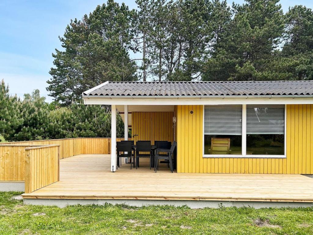 a yellow house with a table and chairs on a deck at 5 person holiday home in R dby in Rødby