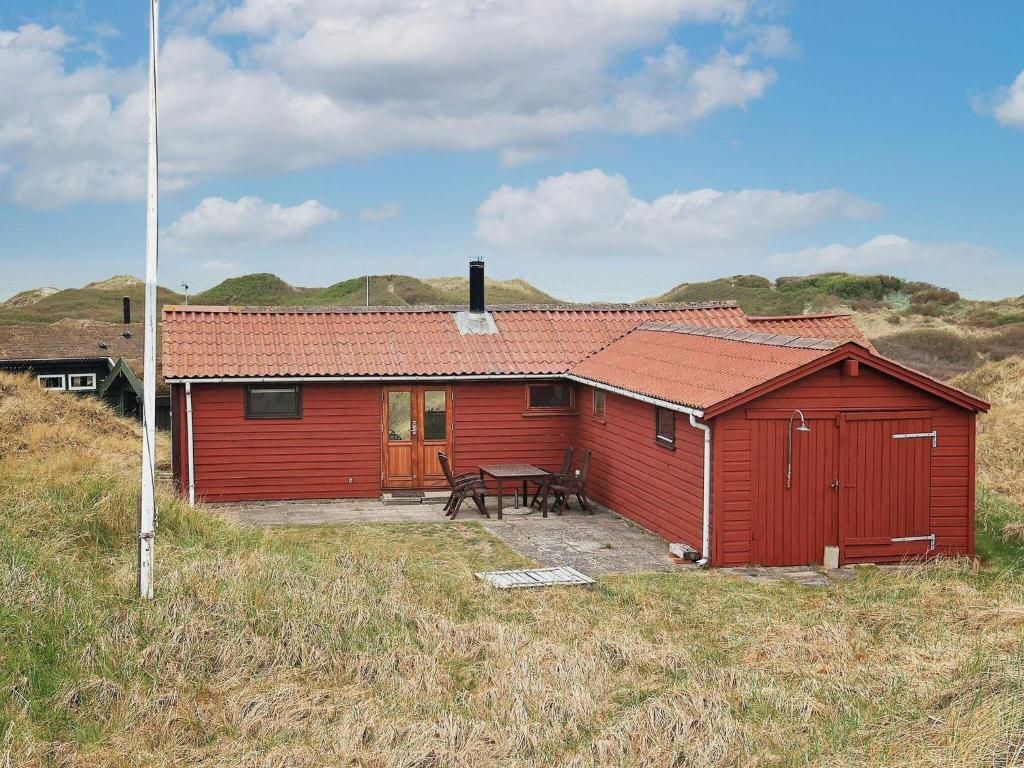 een rode schuur met een picknicktafel ervoor bij Three-Bedroom Holiday home in Løkken 31 in Grønhøj