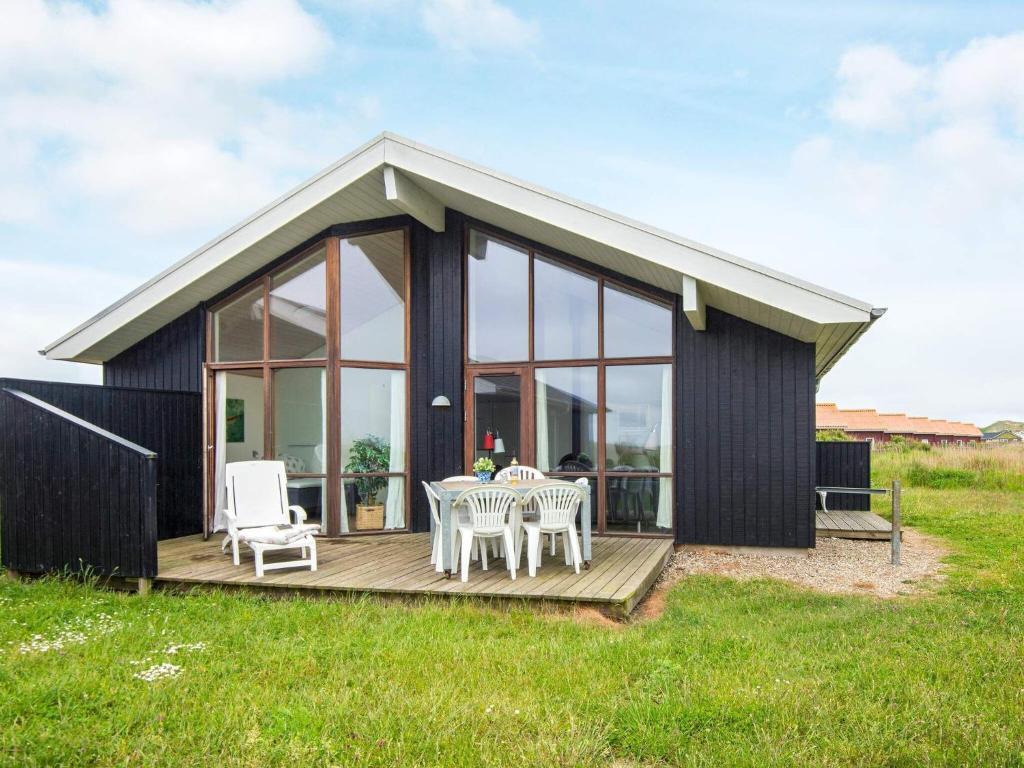 Cabaña negra con mesa y sillas en la terraza en 8 person holiday home in Ulfborg en Thorsminde
