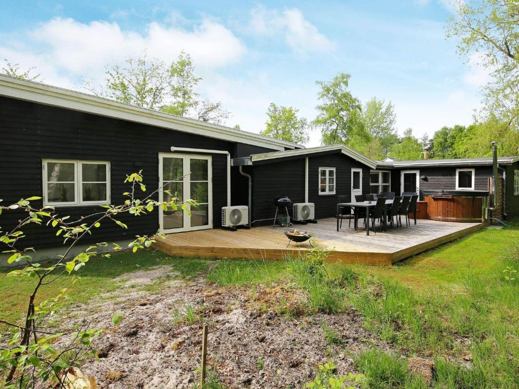una casa negra con una terraza de madera delante de ella en Holiday home Vig XXXV, en Vig