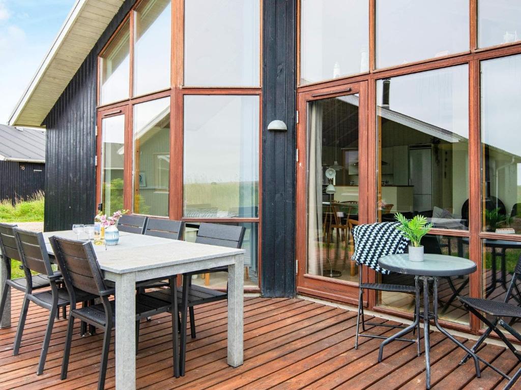 ThorsmindeにあるThree-Bedroom Holiday home in Ulfborg 4の木製デッキ(テーブル、椅子付)