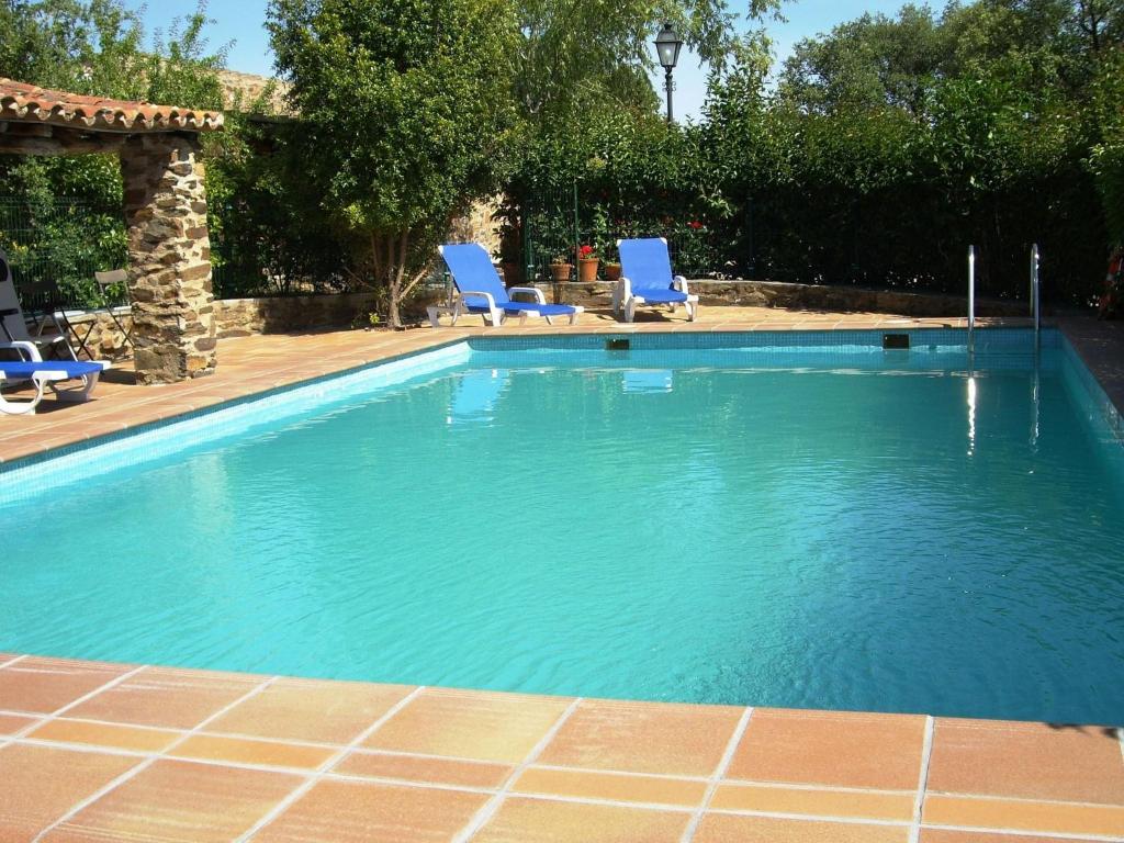 una piscina con 2 sillas azules. en Studio on rural authentic finca with shared pool, en La Borrega