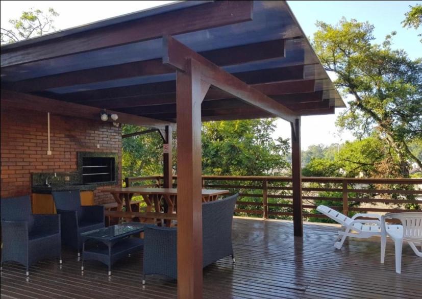 a patio with a wooden deck with a table and chairs at Apart Hotel Pousada do Serrano in Gramado