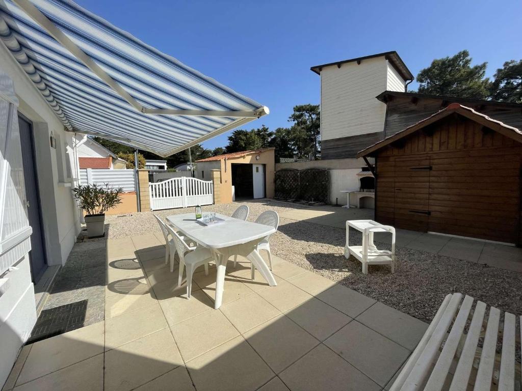 un patio avec une table et des chaises blanches et une grange dans l'établissement Charmante maison à Saint-Jean-de-Monts, 400m de la plage, terrasse, jardin, parking et ménage inclus - FR-1-224C-198, à Saint-Jean-de-Monts