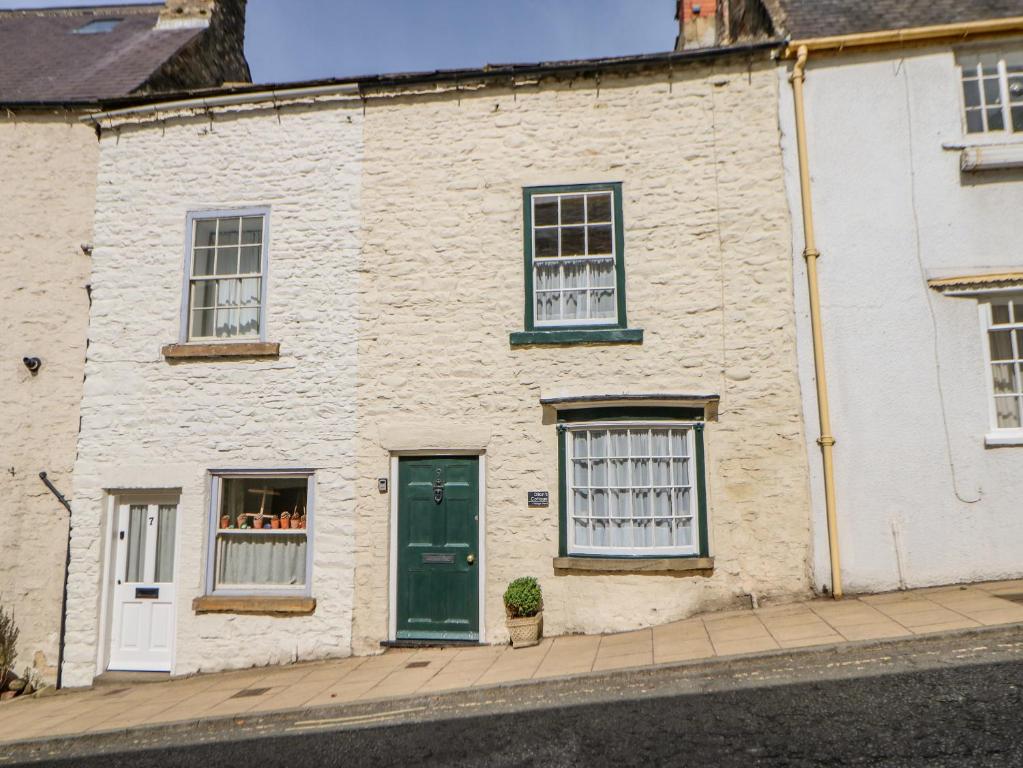 a white brick house with a green door and windows at Dillons Cottage in Richmond