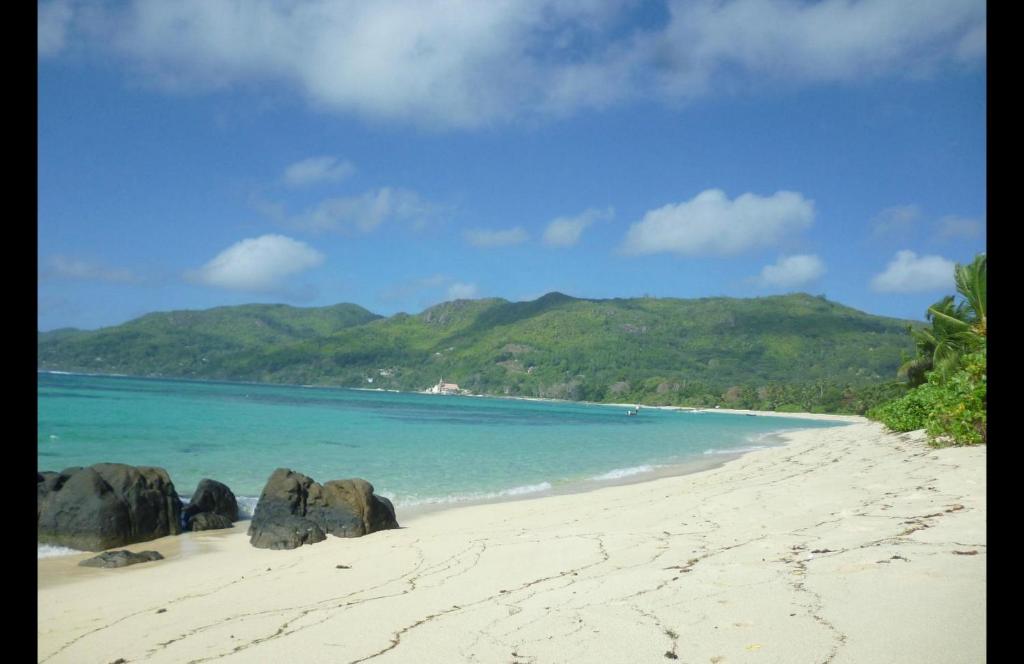 una spiaggia con rocce nella sabbia e nell'oceano di Royale Self Catering Apartments ad Anse Royale
