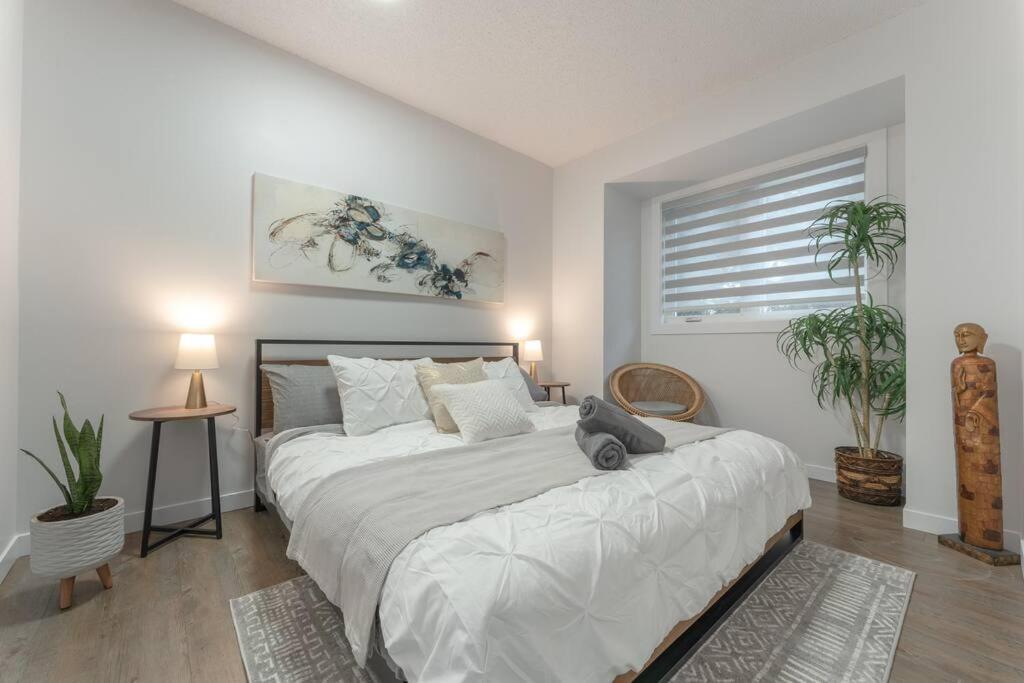 una camera da letto con un grande letto bianco con due piante di Chic Romantic3bed patio WIFI quiet retreat parking a Calgary