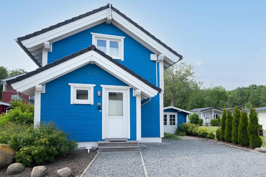 ein blaues Haus mit einer weißen Tür in einer Einfahrt in der Unterkunft Seepark Süssau Ferienhaus Seehund 4 in Süssau