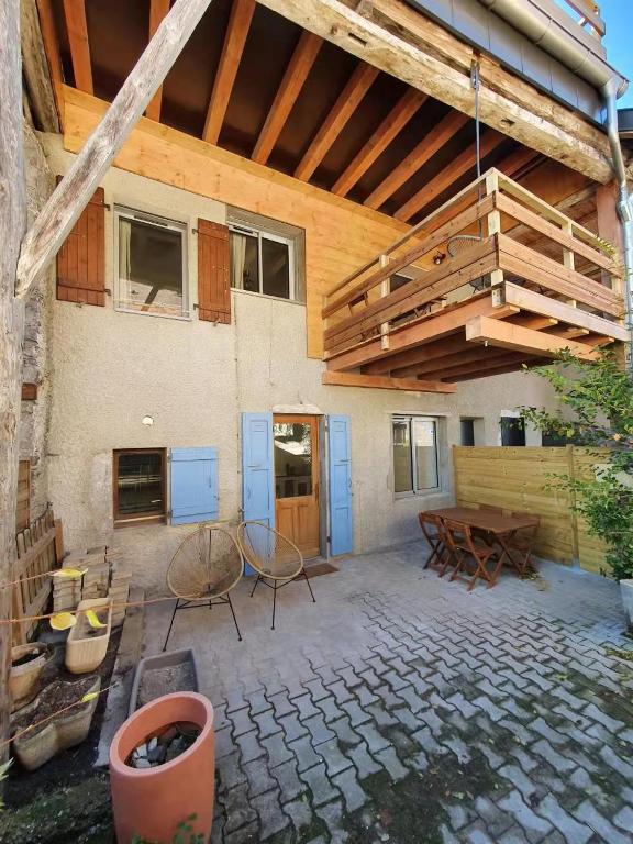 une terrasse avec un toit en bois, une table et des chaises dans l'établissement LA MAISON DU LAC, à Doussard