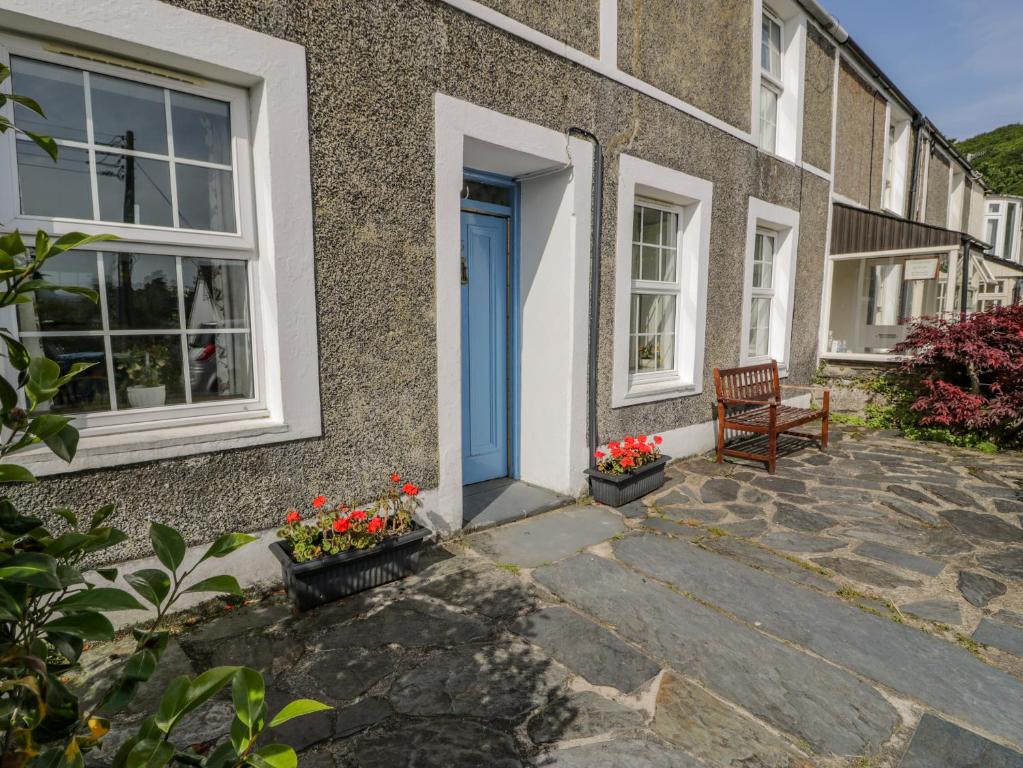 ein Haus mit einer blauen Tür und einer Bank in der Unterkunft 6 Glyn Terrace in Porthmadog