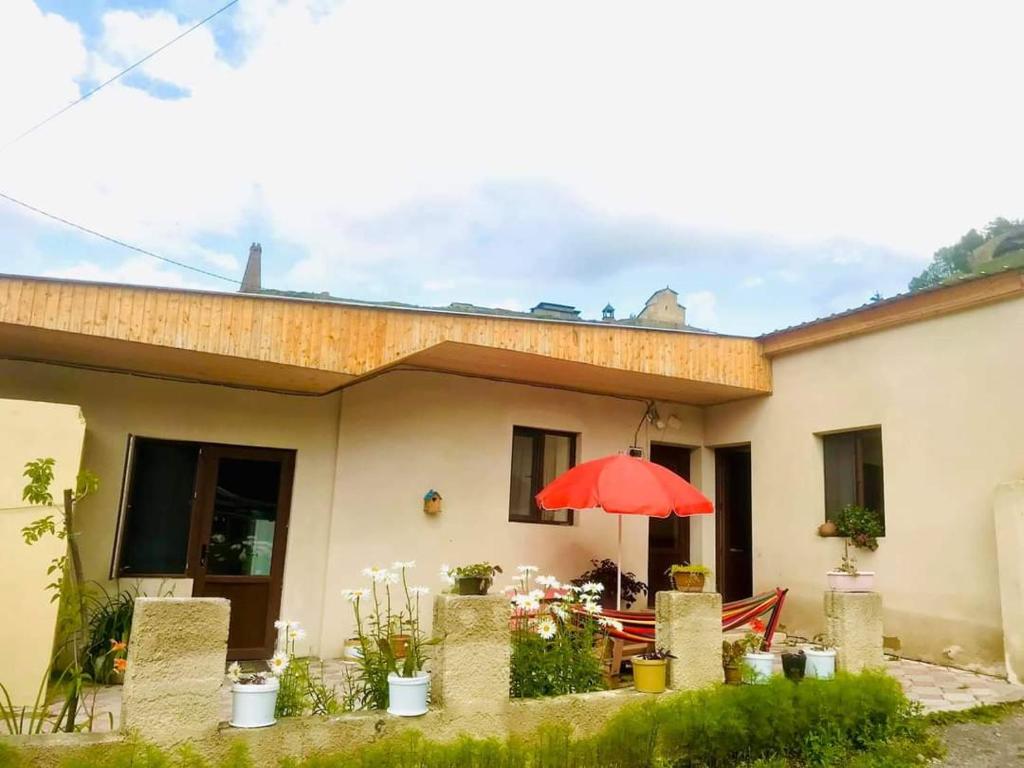 een huis met een rode paraplu ervoor bij Guesthouse and Cottage Nicolo in Kazbegi