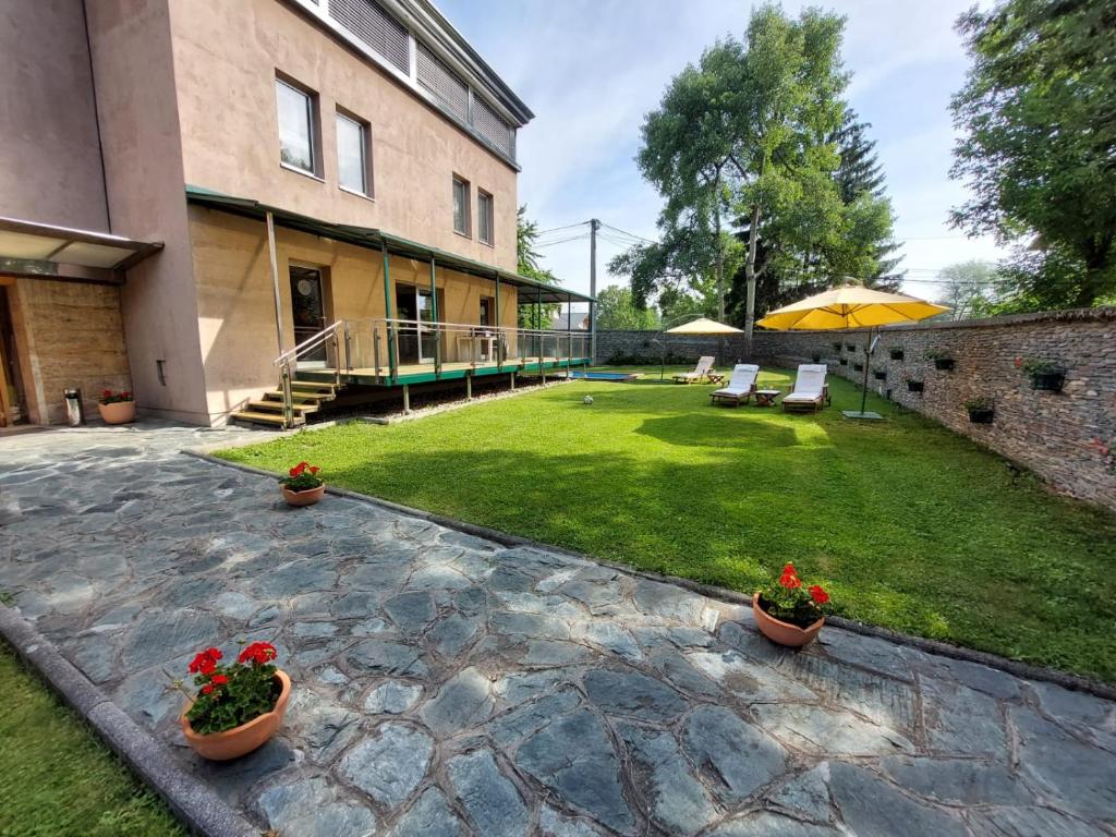 a backyard with a patio and a lawn with plants at Hotel Brass in Sarajevo