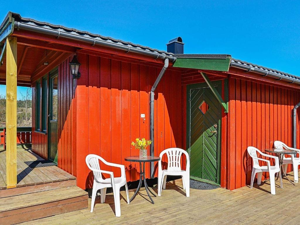 ein rotes Gebäude mit Stühlen und einem Tisch auf einer Terrasse in der Unterkunft Two-Bedroom Holiday home in Lyngdal 1 in Korshamn