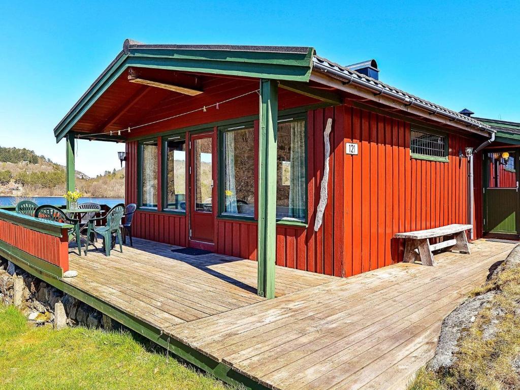 a red house with a wooden deck with a table at 5 person holiday home in lyngdal in Korshamn