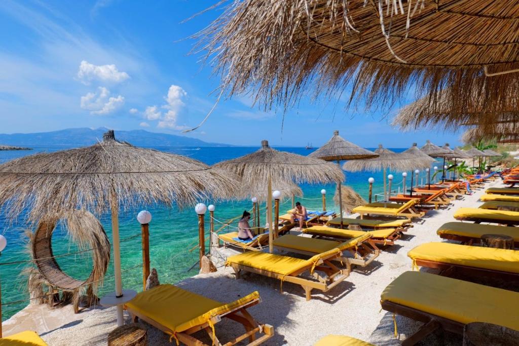 una fila de sillas de playa y sombrillas en una playa en Siro Kerma Private Beach Villa en Sarandë