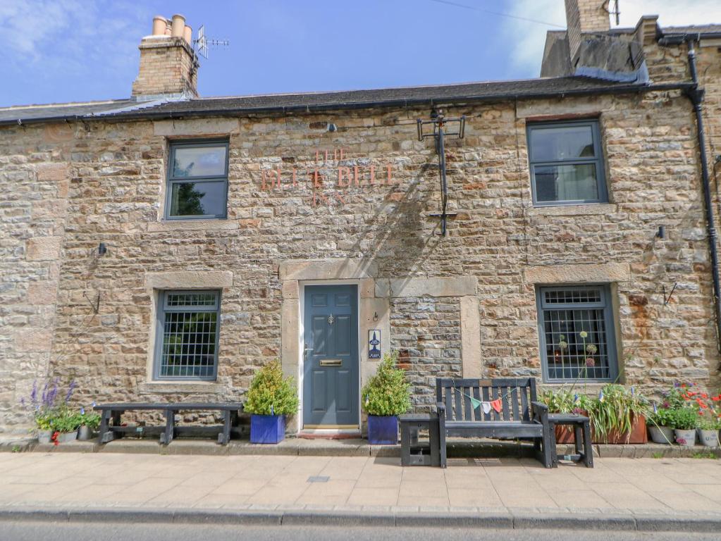 a brick building with two benches in front of it at Grace Cottage in Bishop Auckland