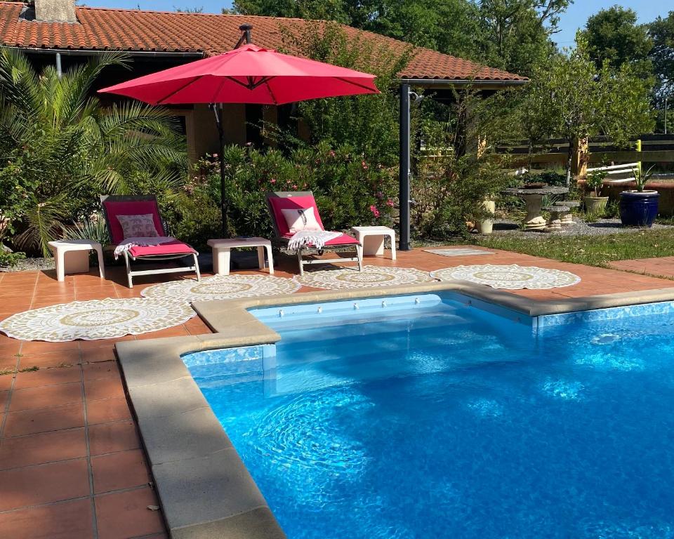 uma piscina com duas cadeiras e um guarda-sol vermelho em l'hacienda em Saint-Pierre-du-Mont