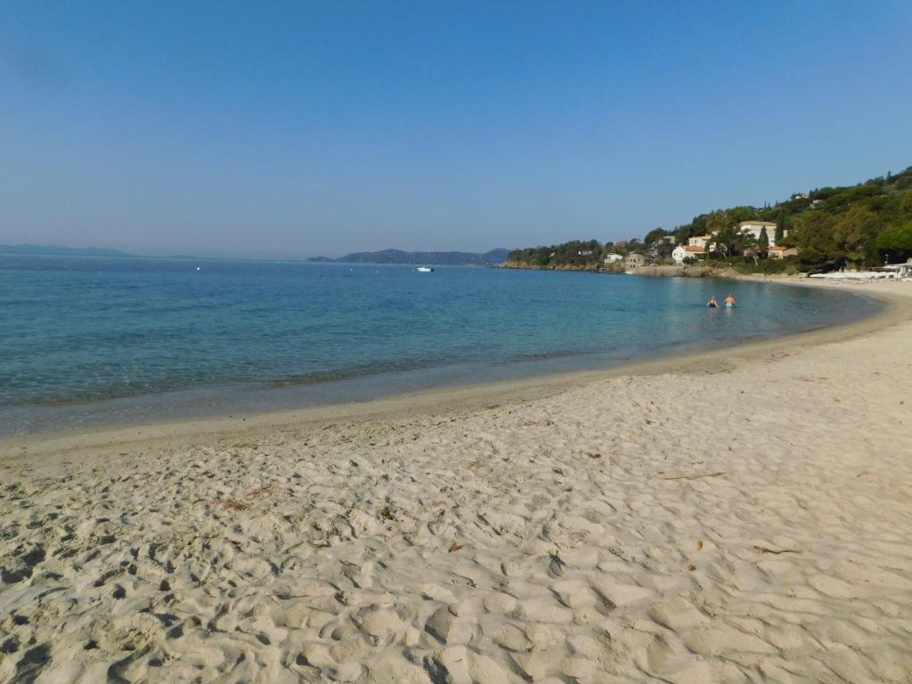 a sandy beach with people swimming in the water at Villa 54 - Plage Aiguebelle 250m in Le Lavandou