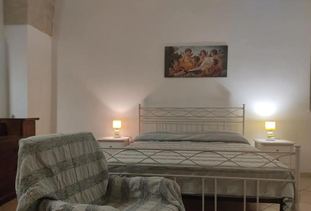 ein Schlafzimmer mit einem Bett, einem Stuhl und einem Gemälde in der Unterkunft Casa Stella in Uggiano la Chiesa