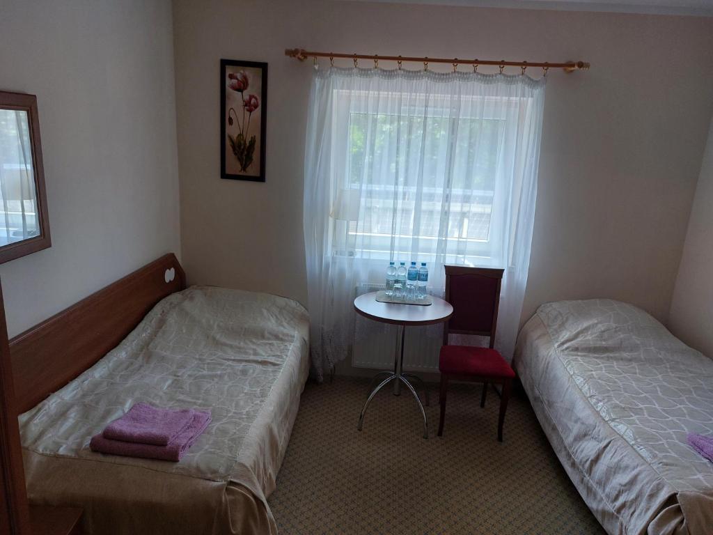 sypialnia z 2 łóżkami, stołem i oknem w obiekcie Ośrodek ANKAR w mieście Pokrzywna