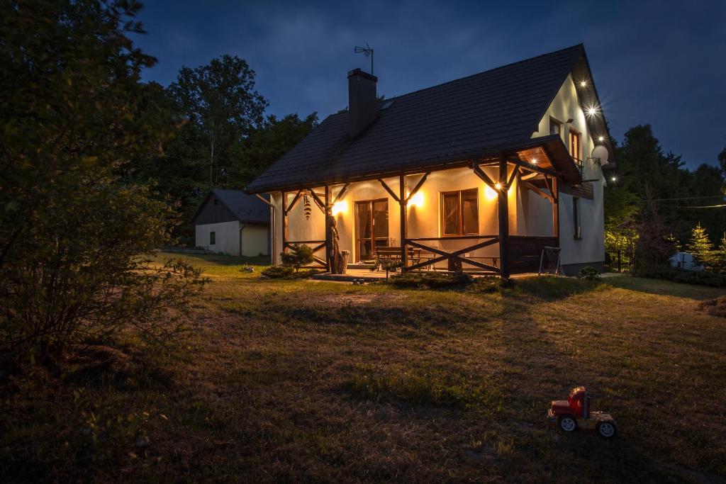 a small white house with lights in the yard at Zakamarek- dom z ogrodem Góry Świętokrzyskie bez sąsiadów, las, 10 osób na wyłączność in Lechów
