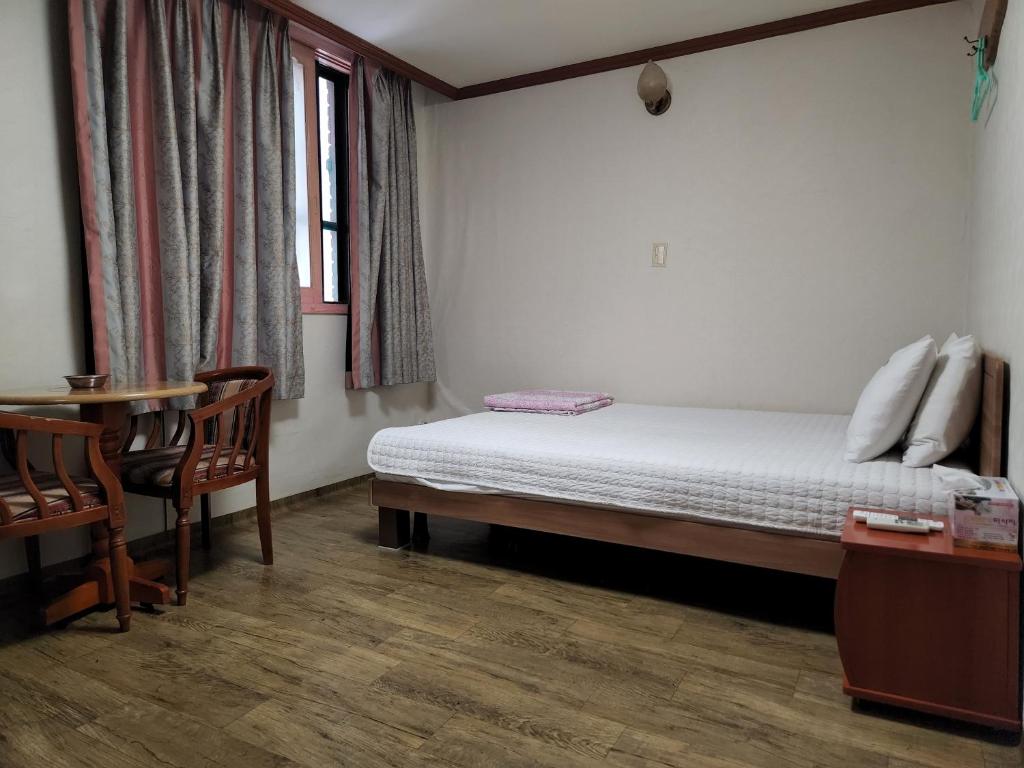 a bedroom with a bed and a table and chairs at Daeho Motel in Busan