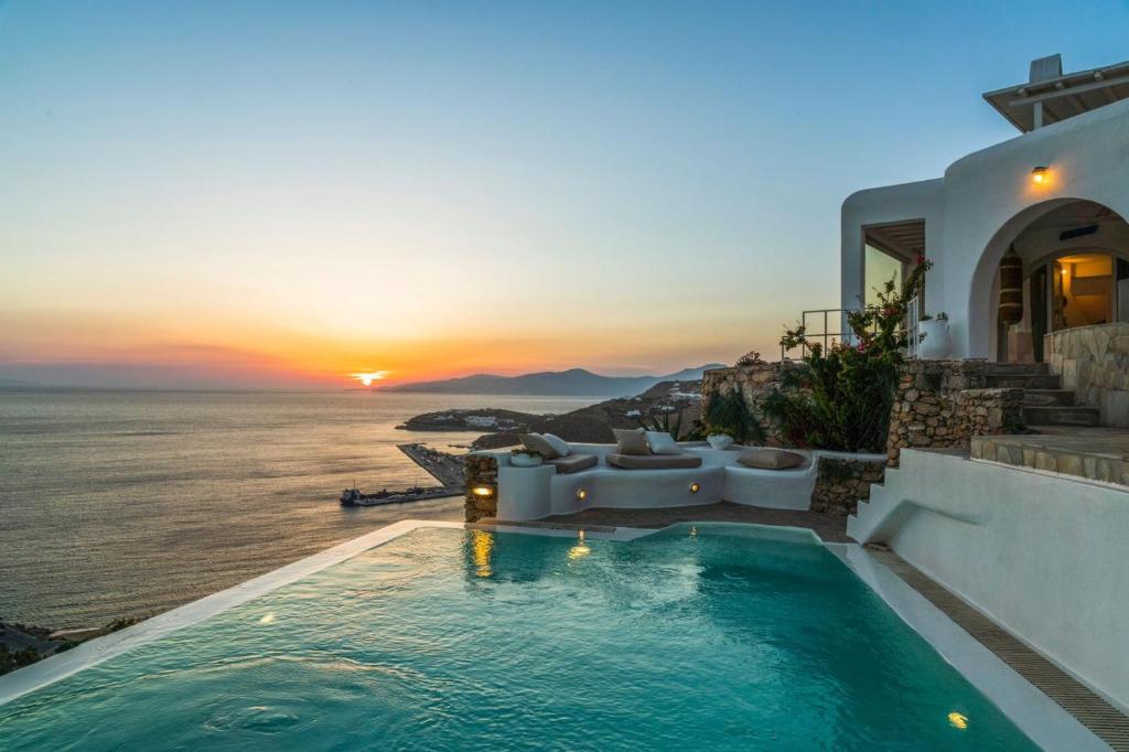 a pool with a view of the ocean at sunset at Villa Ruby by Mykonos Rocks in Mýkonos City