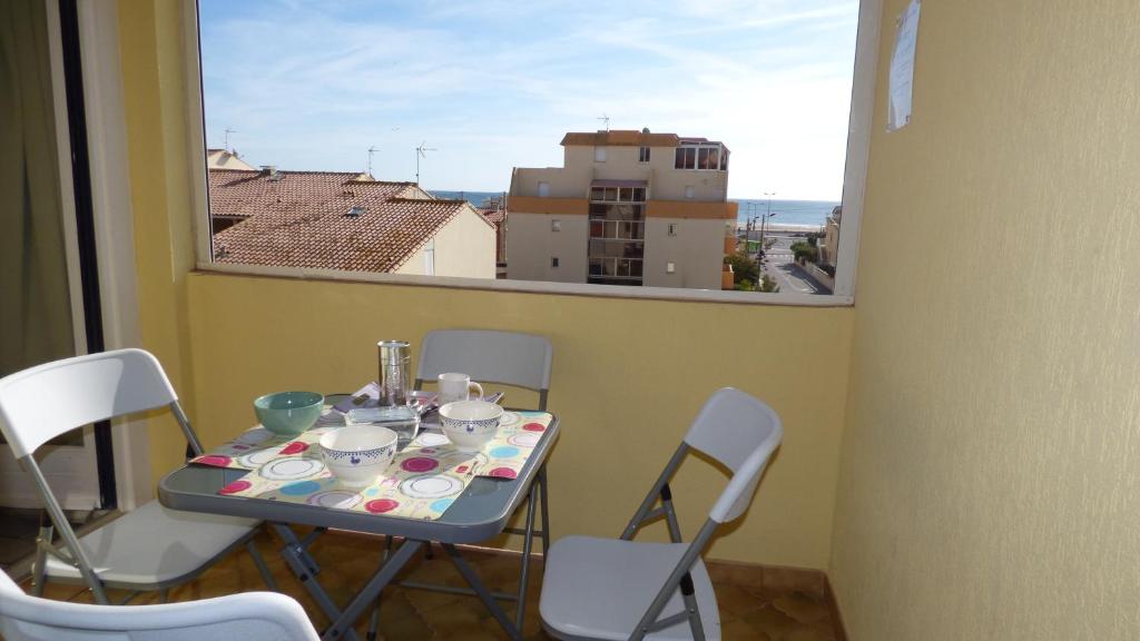 une table et des chaises dans une pièce avec une fenêtre dans l'établissement Joli T2 vue mer, proche mer, parking, Narbonne-plage, à Narbonne-Plage
