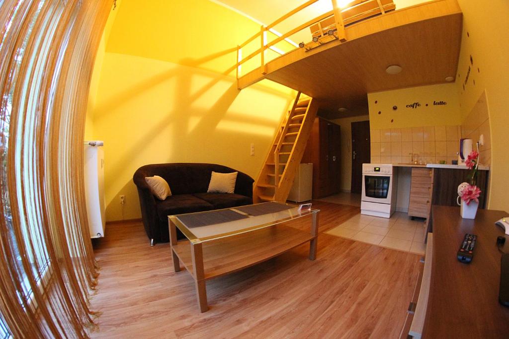 een woonkamer met een bank, een tafel en een trap bij Apartamenty Green Garden in Racibórz