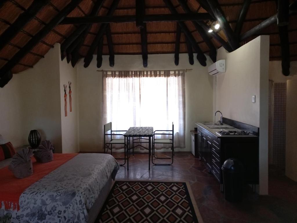 Schlafzimmer mit einem Bett, einem Tisch und einem Fenster in der Unterkunft Roidina Safari Lodge in Omaruru