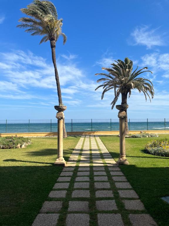 two palm trees on a path near the beach at Sol y 1ª linea de playa Urbanización Lubina sol in Sitio de Calahonda