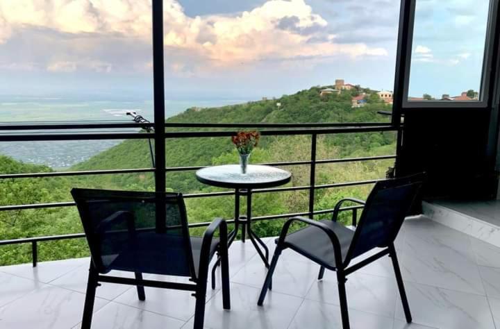 a table and chairs in a balcony with a view at Hotel Martinichi in Sighnaghi