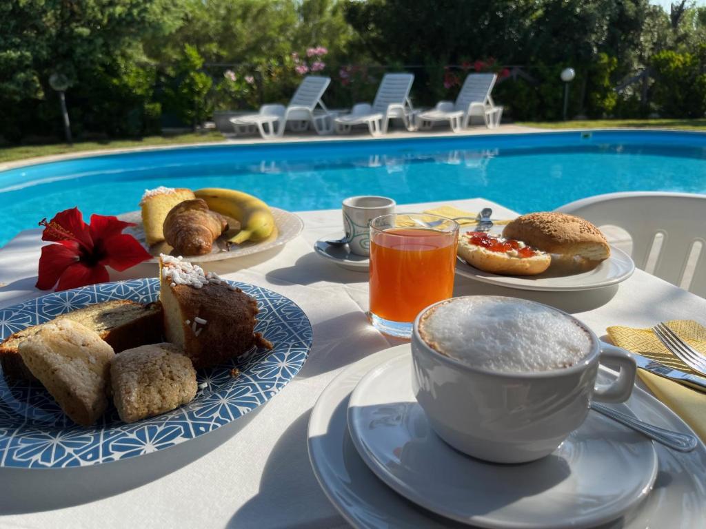 a table with plates of food and a cup of coffee at Hotel Frassetto in Santa Teresa Gallura