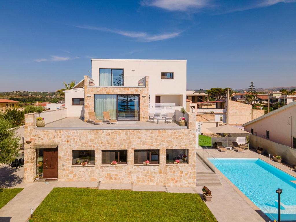 een villa met een zwembad en een huis bij Elaia Rooms in Noto Marina