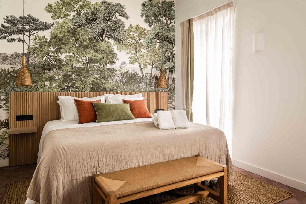 a bedroom with a large bed and a wall with trees at El Consul Mao - Hotel Boutique in Mahón