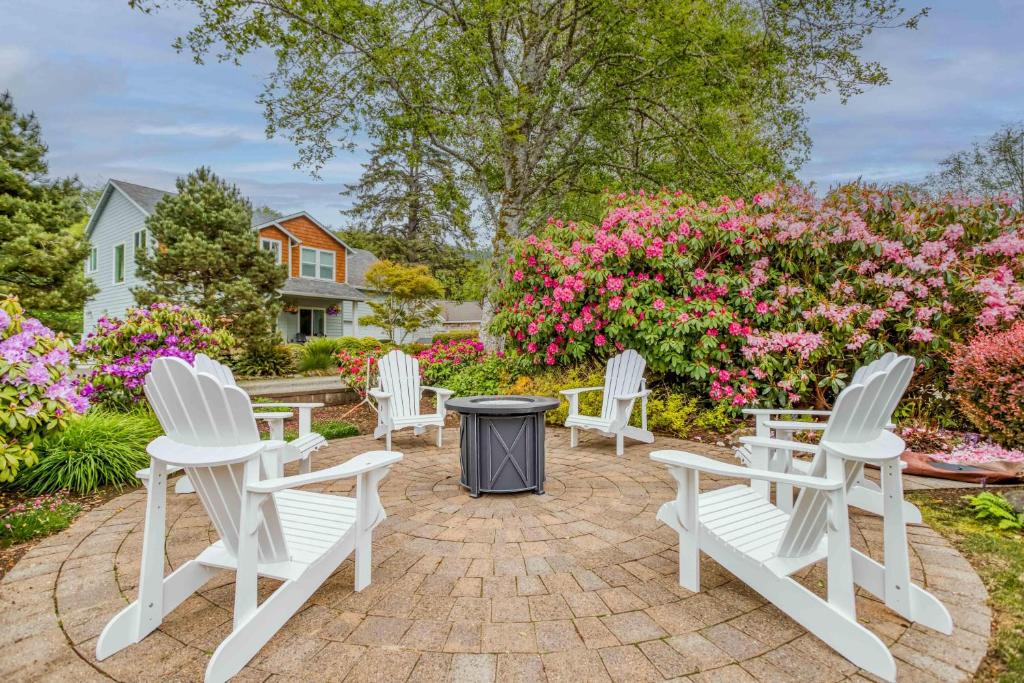 a group of white chairs sitting on a patio with flowers at Family Tides - Meredith Lodging in Neskowin