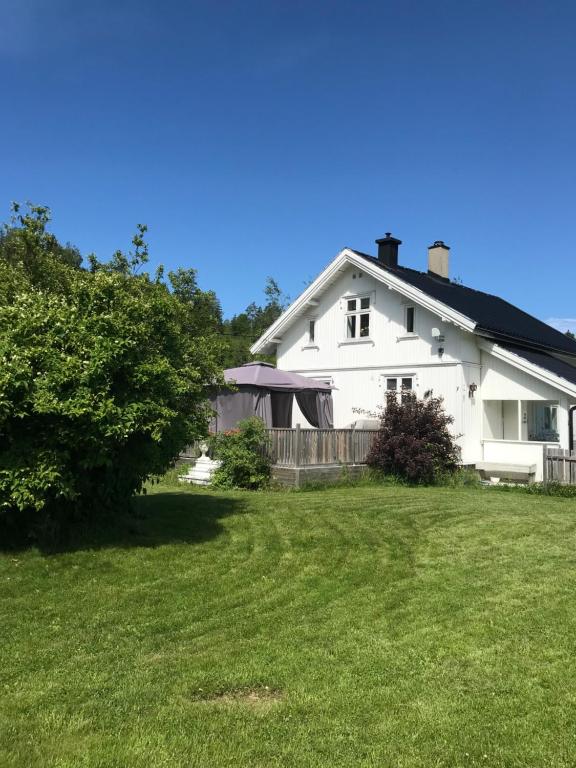 a white house with a fence and a yard at Småbruket stall solheim in Rødby