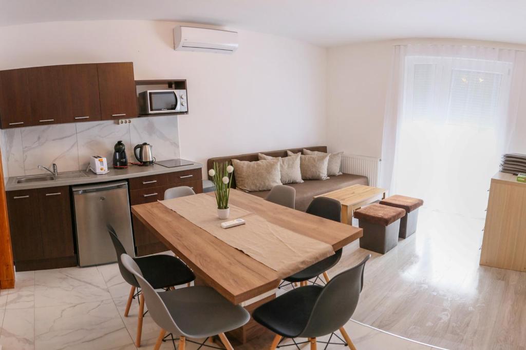 uma cozinha e sala de estar com uma mesa de madeira e cadeiras em Família Apartmanház em Sárvár