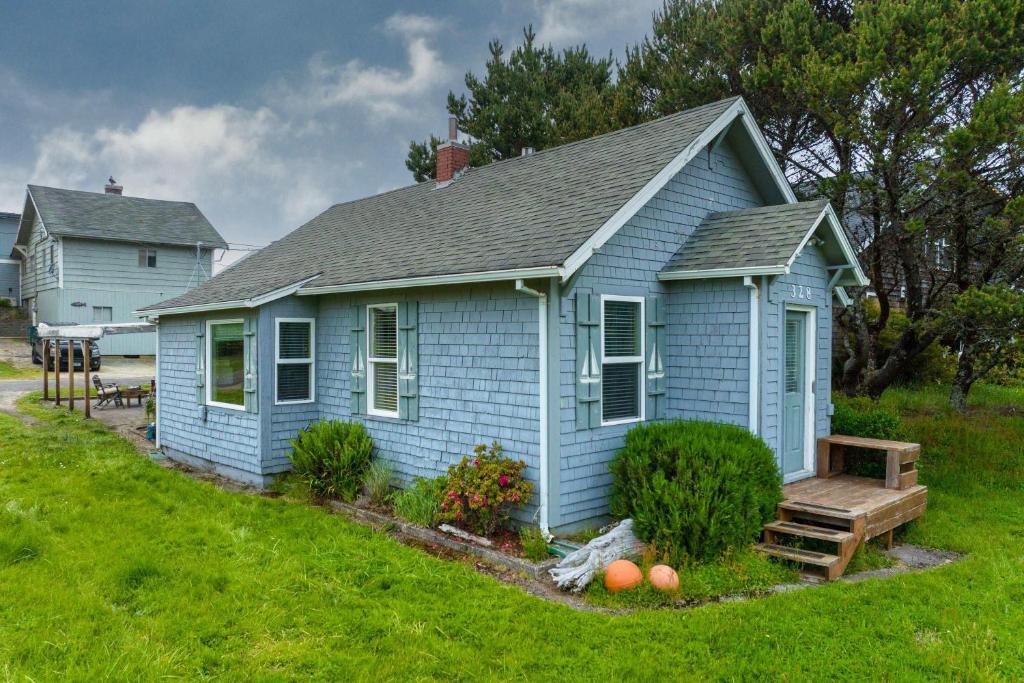 une maison bleue avec un banc devant elle dans l'établissement Serenity Cottage, à Rockaway Beach