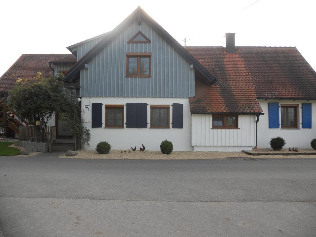 a white house with blue shutters on a street at Ferienwohnung Scholter in Eichstegen