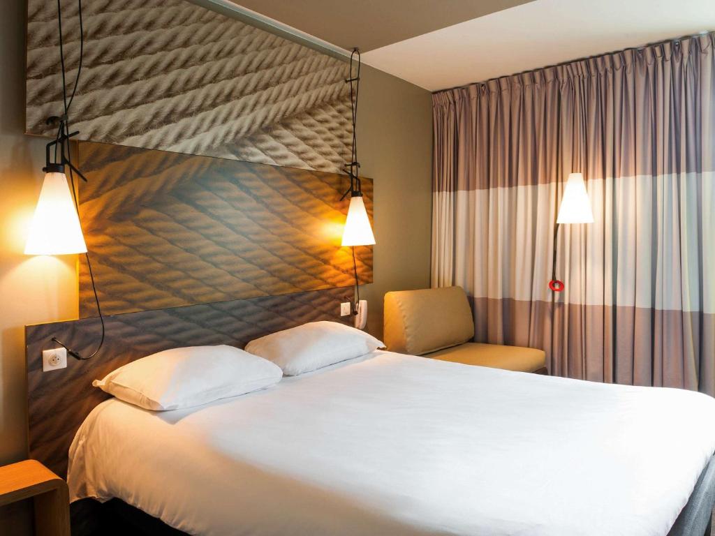 a hotel room with a large bed and a chair at ibis Paris La Defense Courbevoie in Courbevoie