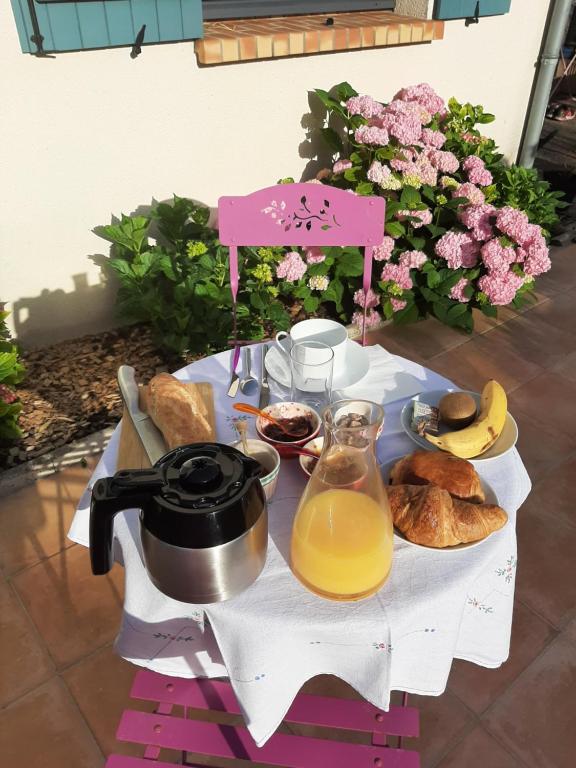 un tavolo con colazione a base di pane e succo d'arancia di Au Chat Perché chambre double a Mareil-sur-Mauldre