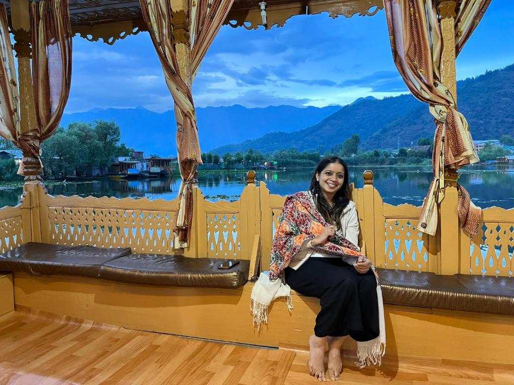 a woman sitting on a bench in front of a lake at Raja's Palace Houseboat - Kashmir in Srinagar