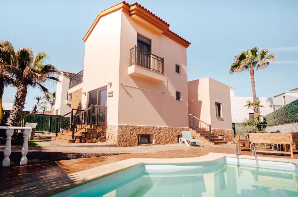 a villa with a swimming pool in front of a house at International Surf Camp ONLY SURF in Corralejo